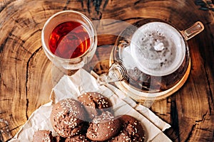 Teapot with black tea and homemade chocolate cookies on a brown natural wooden background