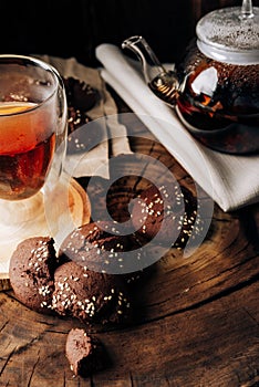 Teapot with black tea and homemade chocolate cookies on a brown natural wooden background