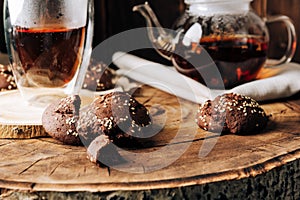 Teapot with black tea and homemade chocolate cookies on a brown natural wooden background