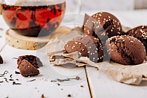 Teapot with black tea and homemade chocolate cookies on a white natural wooden background