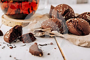 Teapot with black tea and homemade chocolate cookies on a white natural wooden background