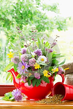 Teapot with bouquet of healing herbs and flowers