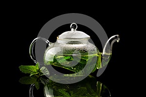 Teapot with brewed mint tea on a black