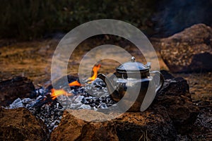Teapot on campfire making tea and coffe on fire and flames photo