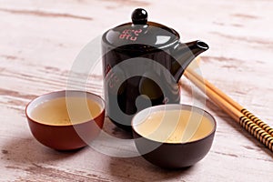 teapot and cups of green tea on a white wooden background