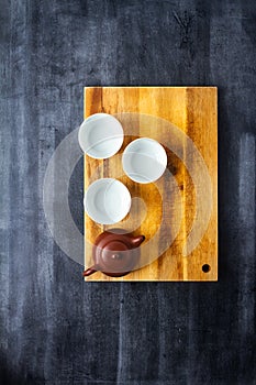 Teapot and cups on wooden cutting board