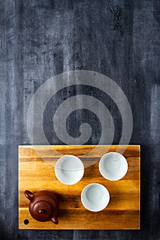 Teapot and cups on wooden cutting board