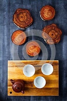 Teapot and cups on wooden cutting board with tree trunk slices