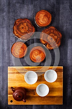 Teapot and cups on wooden cutting board with tree trunk slices