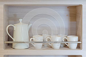 Teapot and cups on wooden shelf