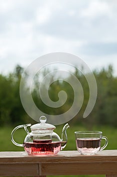 Teapot with fragrant herbal tea on a background of nature