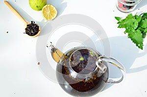 teapot full of tea on a background of green foliage on a wooden table, next to forest berries, raspberries and