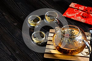 Teapot and glass cup with blooming tea flower