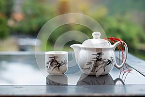 Teapot and hot tea to cup on wood table against tea garden view background in the morning, Ban Rak Thai village, Mae Hong Son