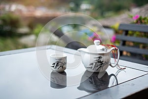 Teapot and hot tea to cup on wood table against tea garden view background in the morning, Ban Rak Thai village, Mae Hong Son