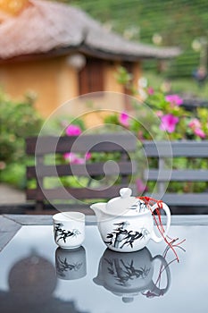 Teapot and hot tea to cup on wood table against tea garden view background in the morning, Ban Rak Thai village, Mae Hong Son