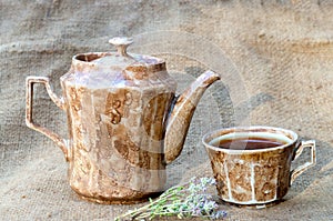 teapot and a mug with tea on burlap.