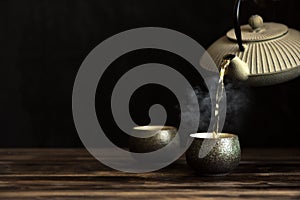 Teapot pouring tea into cups