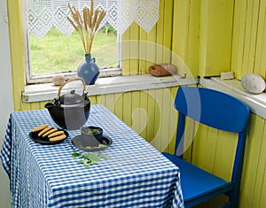 Teapot with tea cup and cookie on table blue chair