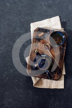 Teapot, teacup and Rooibos tea over black stone background