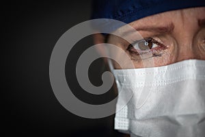 Tearful Stressed Female Doctor or Nurse Crying Wearing Medical Face Mask on Dark Background