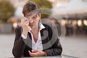 Tearful woman sitting outdoors crying