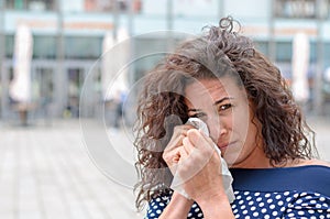 Tearful young woman wiping her eyes