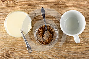 Spoon  condensed milk in bowl  spoon in bowl with instant coffee  empty cup on wooden table. Top view