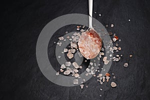 Teaspoon with himalayan pink salt on black slate background