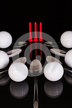 Teaspoons and golf equipments on the black glass table