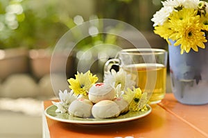 Teatime with Chinese pastry and tea and flower on a orange chair