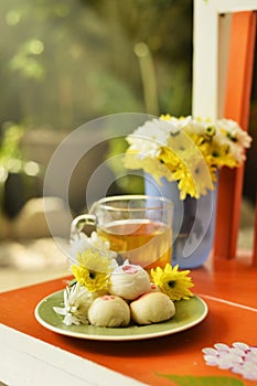 Teatime with Chinese pastry and tea and flower on a orange chair