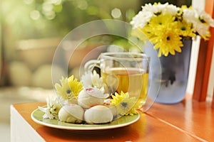 Teatime with Chinese pastry and tea and flower on a orange chair