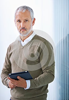 Tech for the modern exec. Portrait of a mature businessman standing with a digital tablet.