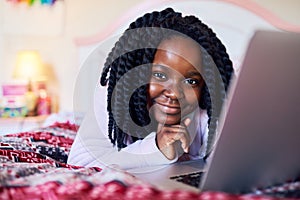 Tech savvy at a young age. an adorable little girl using a laptop while lying on her bed in her bedroom.