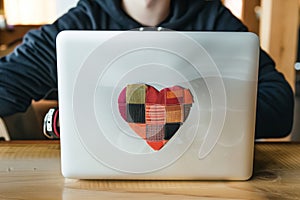 a techie with a laptop sticker in the shape of a patchwork heart photo