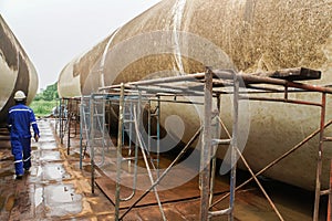 Technical engineer in mechanic jumpsuit with safety helmet on duty on deck with wind turbine tower and scaffolding