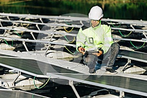 Technical expert in solar energy photovoltaic panels, remote control performs routine actions for system monitoring using clean,