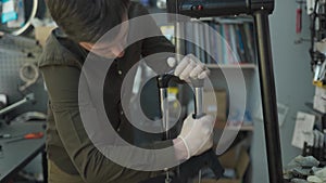 Technical expertise taking care bicycle shop. Attractive mechanic is fixing customer's bicycle at his own workshop