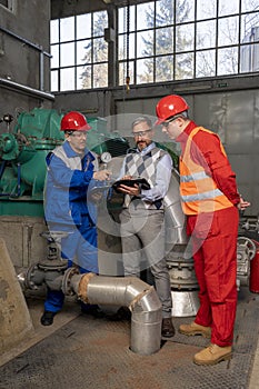 Technical Manager with Digital Tablet Talking to Factory Workers in Mechanical Room