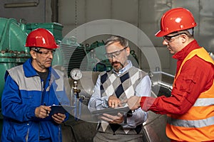 Technical Manager Using Digital Tablet and Discussing About Production Process with Two Power Plant Workers