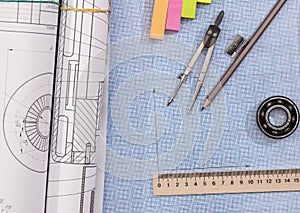 Technical project drawing above graph paper with engineering tools.