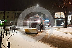 A technical service car with a large bulldozer cleans the city roads from the snow and sprinkles with sand. Unlocking the passage