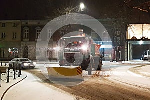 A technical service car with a large bulldozer cleans the city roads from the snow and sprinkles with sand. Unlocking the passage