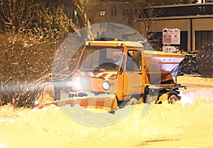A technical service car with a large bulldozer cleans the city roads from the snow and sprinkles with sand. Unlocking the passage