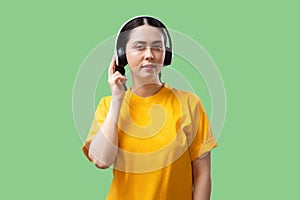 Technical support and hotline. Young Caucasian pretty woman in yellow t-shirt with headphones listening to music on a