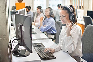 Technical support phone operators in headset working in call centre.
