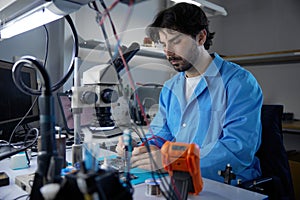 Technician actively engaged in critical work on circuit board while observing under a microscope