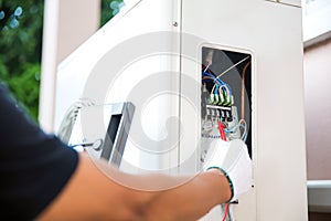 Technician Air-conditioning repairman using measuring equipment checking electric at circuit breaker on outdoor air compressor uni