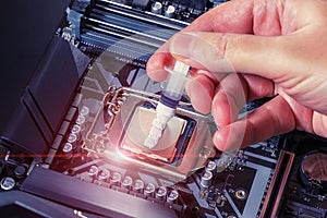 A technician applies white thermal paste to the CPU. Installing a cooler on a PC processor. Assembling or upgrading a